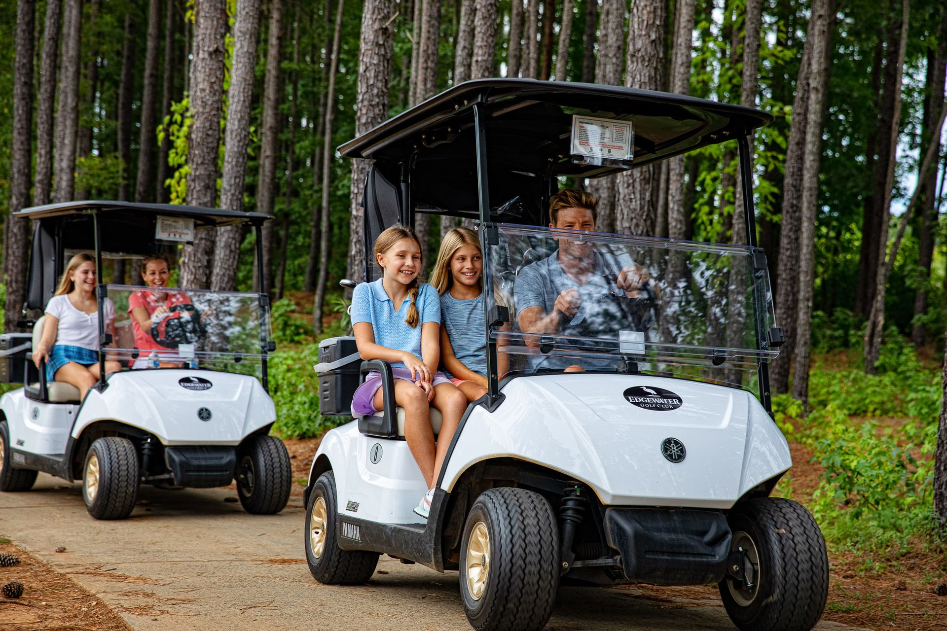 Happy family enjoying golf carts on tree-lined Edgewater trails