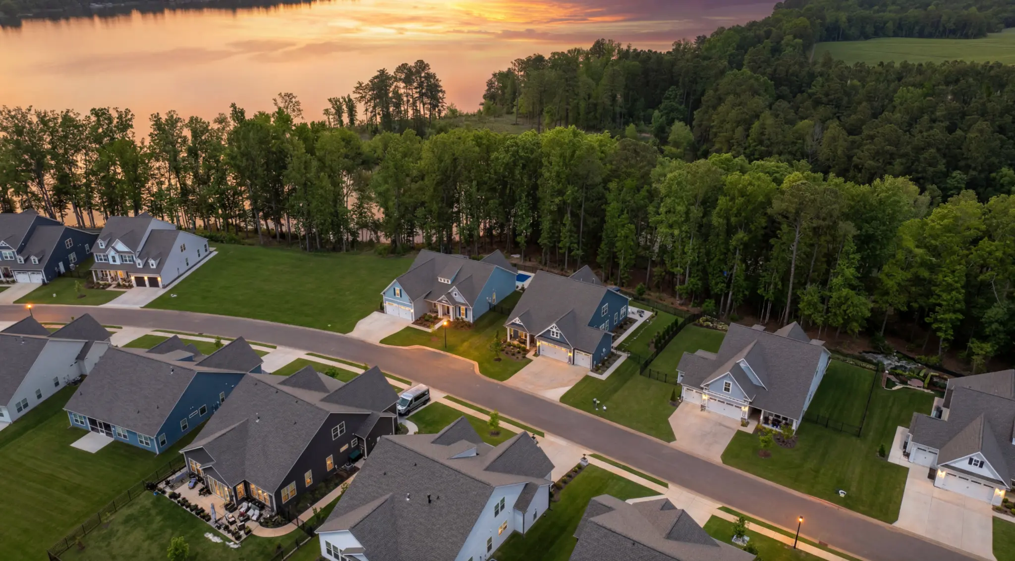 Aerial view at golden hour of True Homes ranch and cottage-style homes at Edgewater in Lancaster South Carolina, with Fishing Creek Lake visible in the background and finished manicured lots
