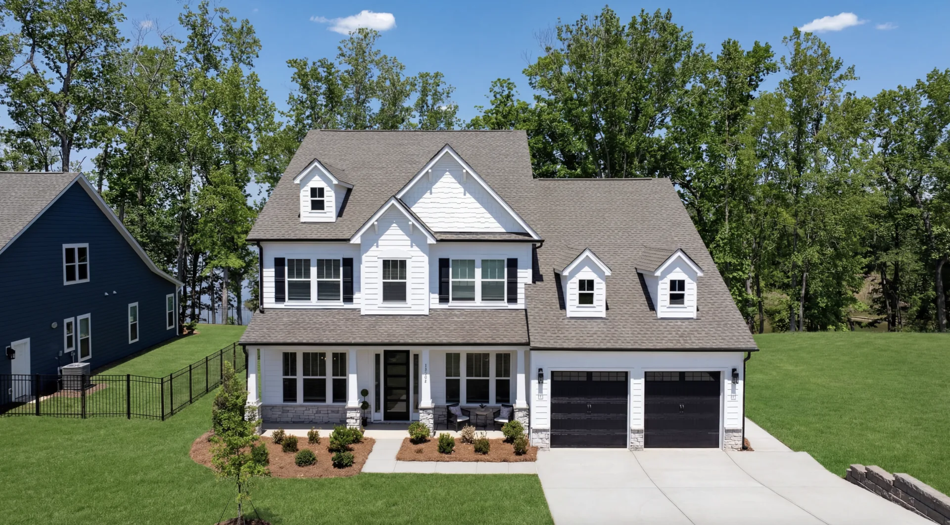 Semi-custom home with white siding, black windows, and shutters